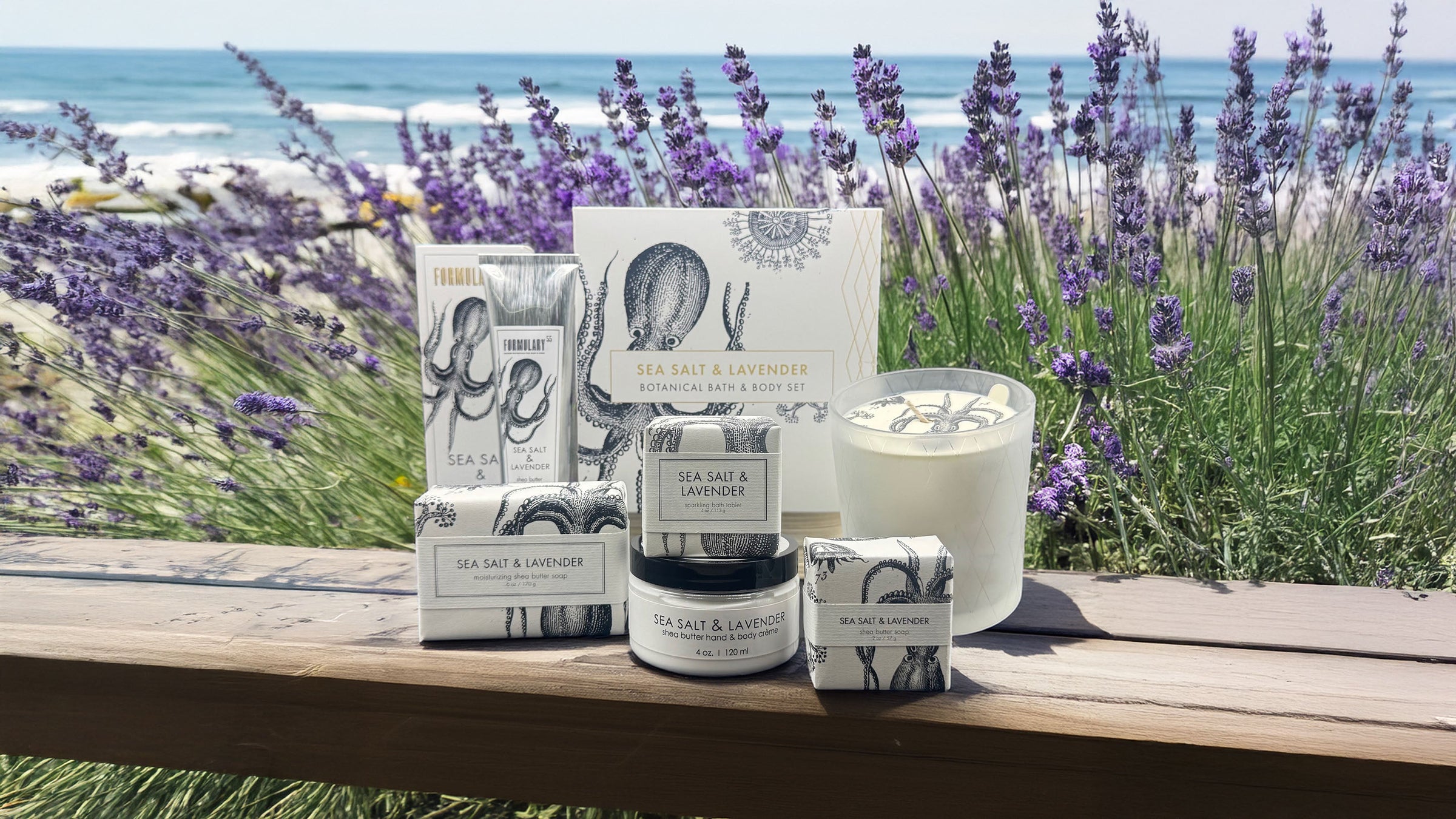 Sea salt and lavender-themed bath products set against a dark backdrop. Includes a boxed set, candle, body scrub, and soap, accented with lavender sprigs and sea salt. Packaging features an octopus illustration.