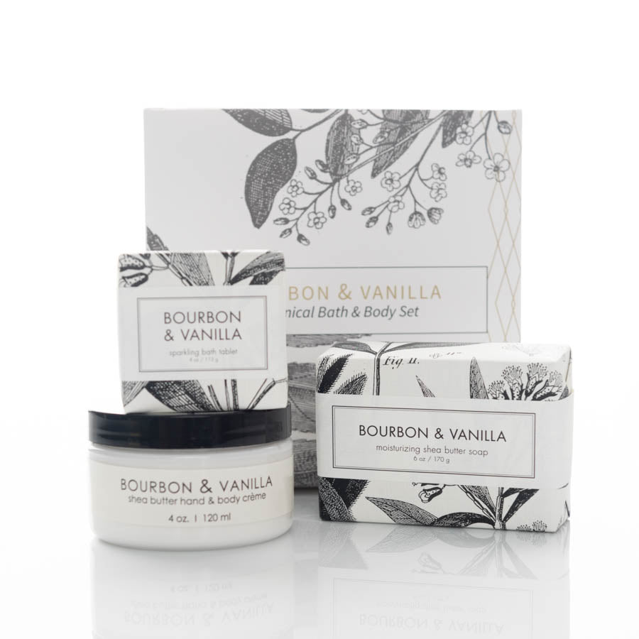 A botanical bath and body set labeled "Bourbon & Vanilla" includes a shea butter hand and body crème, a moisturizing shea butter soap, and a sparkling bath tablet. The packaging features floral illustrations in black and white.
