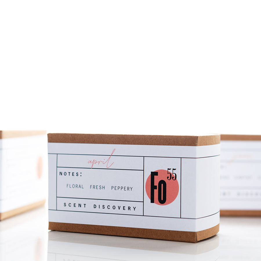 A rectangular cardboard box with a white label on the front featuring the words "Notes: Floral Fresh Peppery", "Scent Discovery", and the number "55" in a red circle with "Fo" in black. The word "April" is handwritten above the notes.
