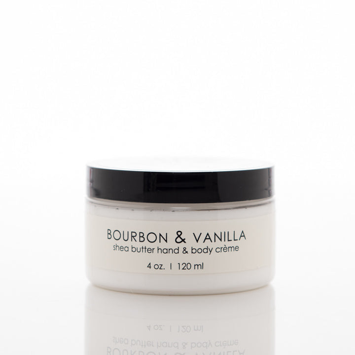 A 4 oz (120 ml) container of shea butter hand and body crème in the scent "Bourbon & Vanilla." The jar is white with a black lid and has a minimalist label design.